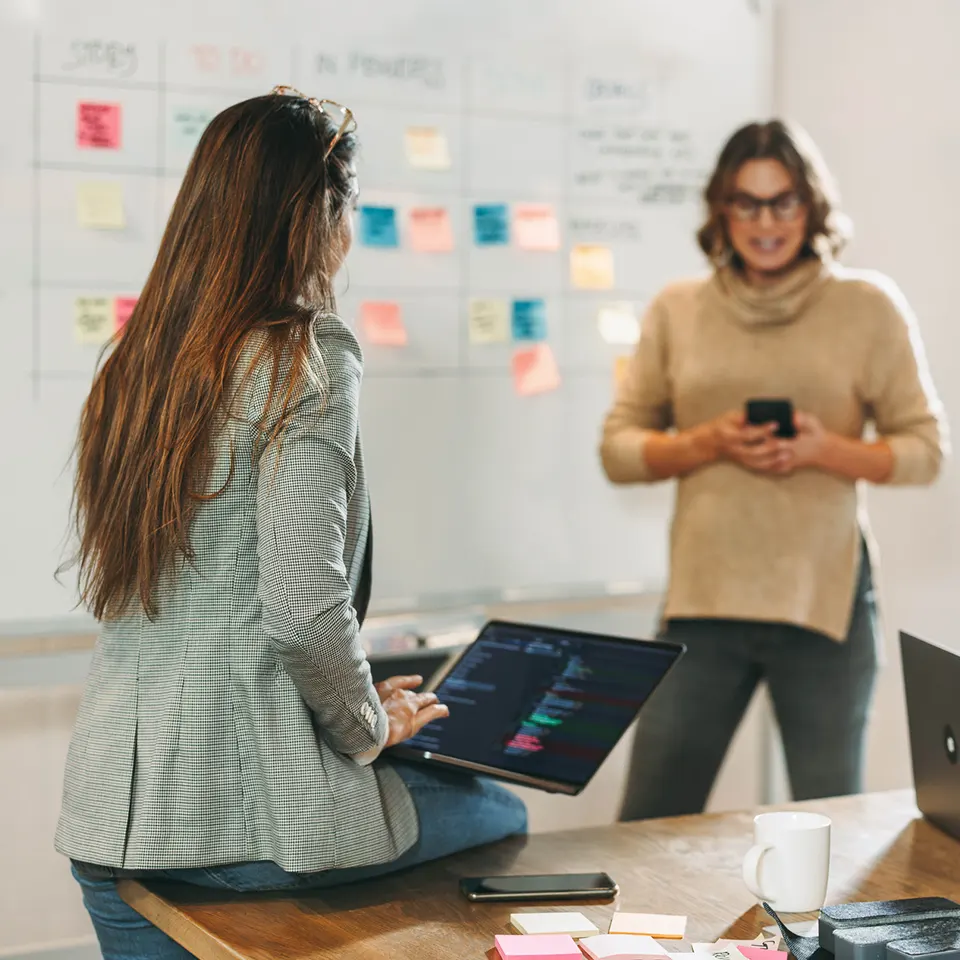 Two content specialists standing in front of a whiteboard featuring a content schedule